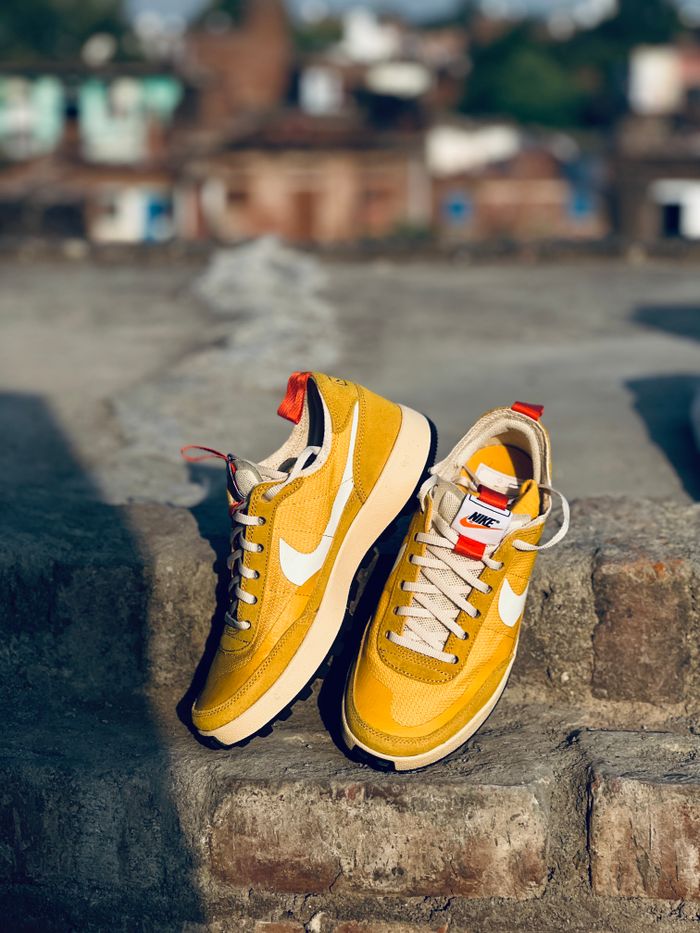 A stylish pair of yellow sneakers resting on a sunlit urban rooftop.