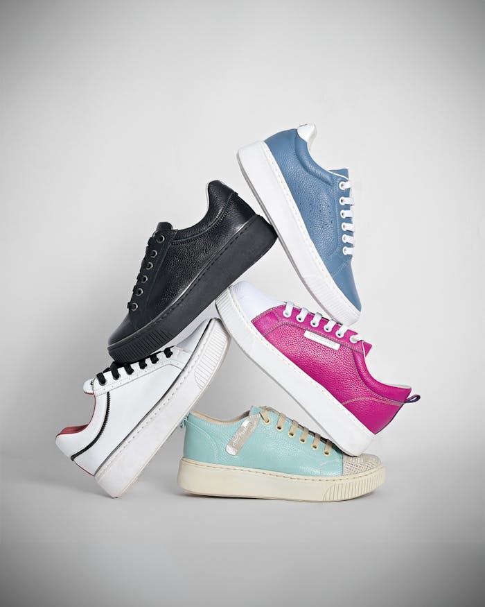 A creative display of five stacked colorful sneakers on a gray background.