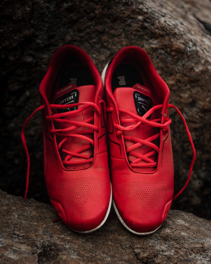 Red leather sneakers placed on rocks, perfect for fashion and sports themes.